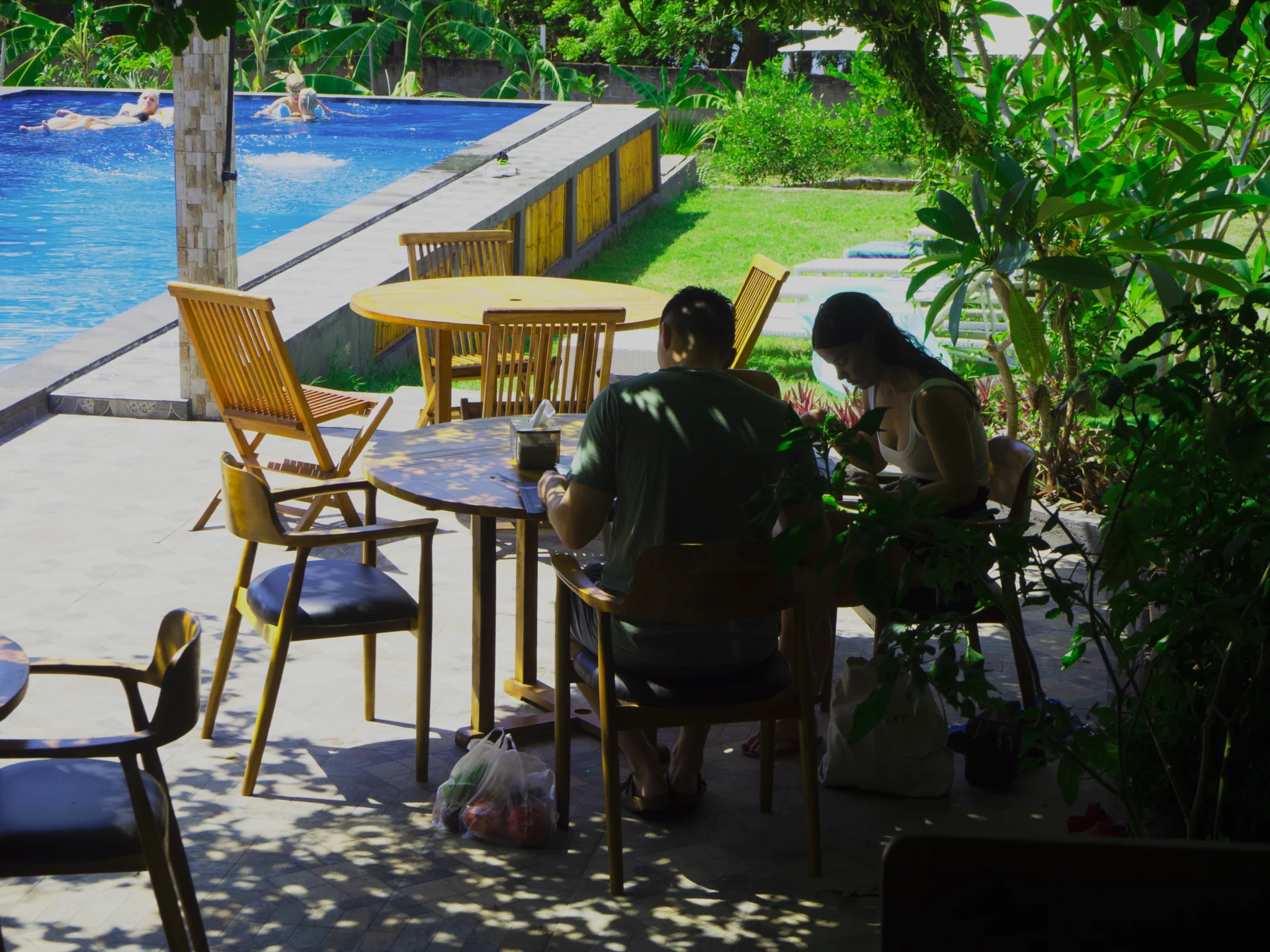 Guests seated at a terrace table near the pool